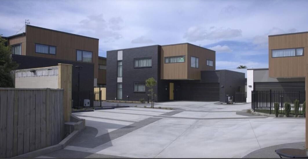 Un edificio residenziale moderno con cortile interno, diversi accessi e viale d'ingresso recintato.