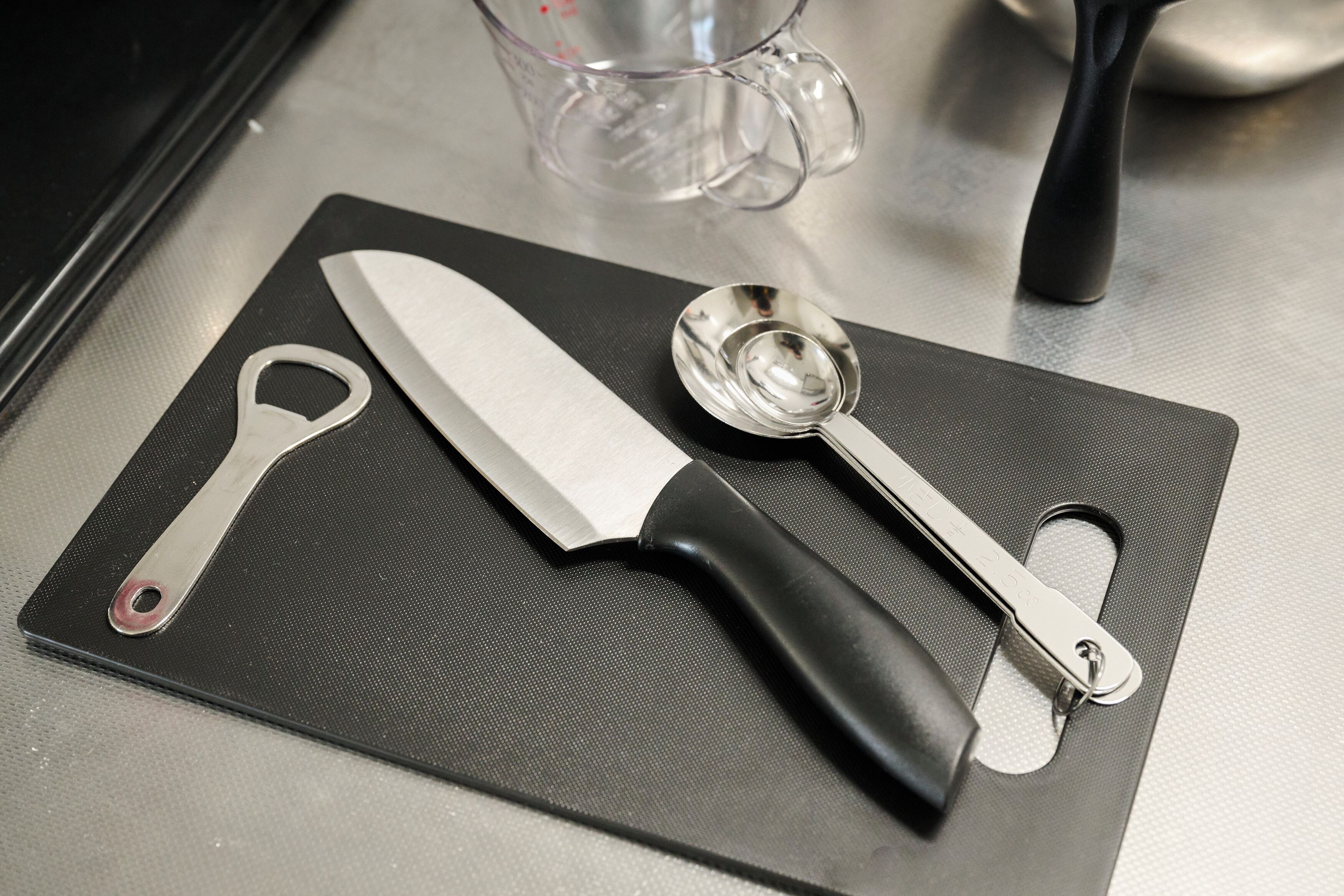 A kitchen counter with a cutting board, a knife, and a measuring spoon.
