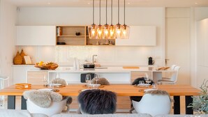 A modern kitchen with a wooden dining table, white chairs, and pendant lighting. - Villa 'Dominica 10' with Sea View, Wi-Fi and Air Conditioning (Estepona)