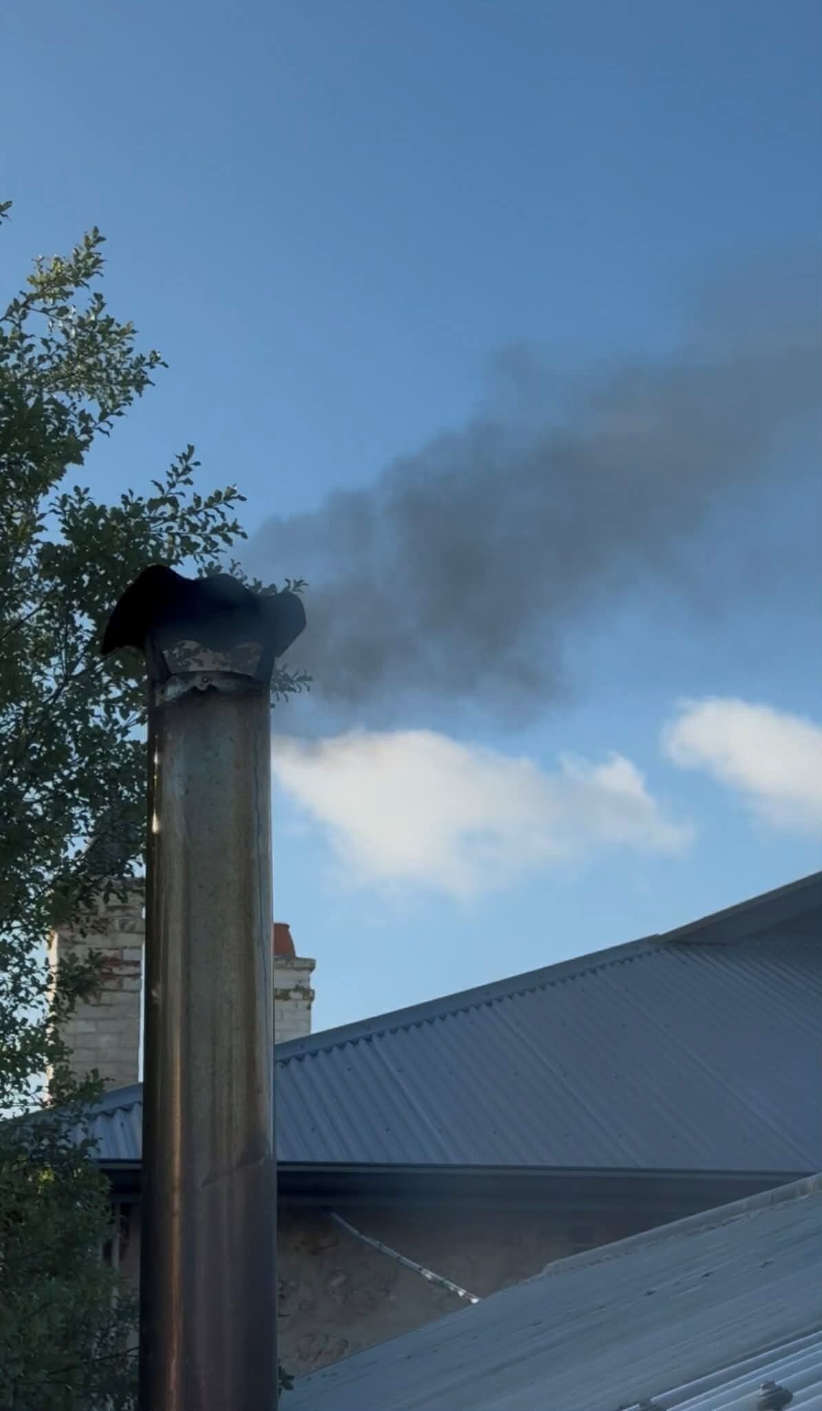 A chimney emitting smoke against a clear sky.