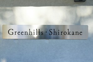 Una placa metálica con la inscripción 'Greenhills·Shirokane'.