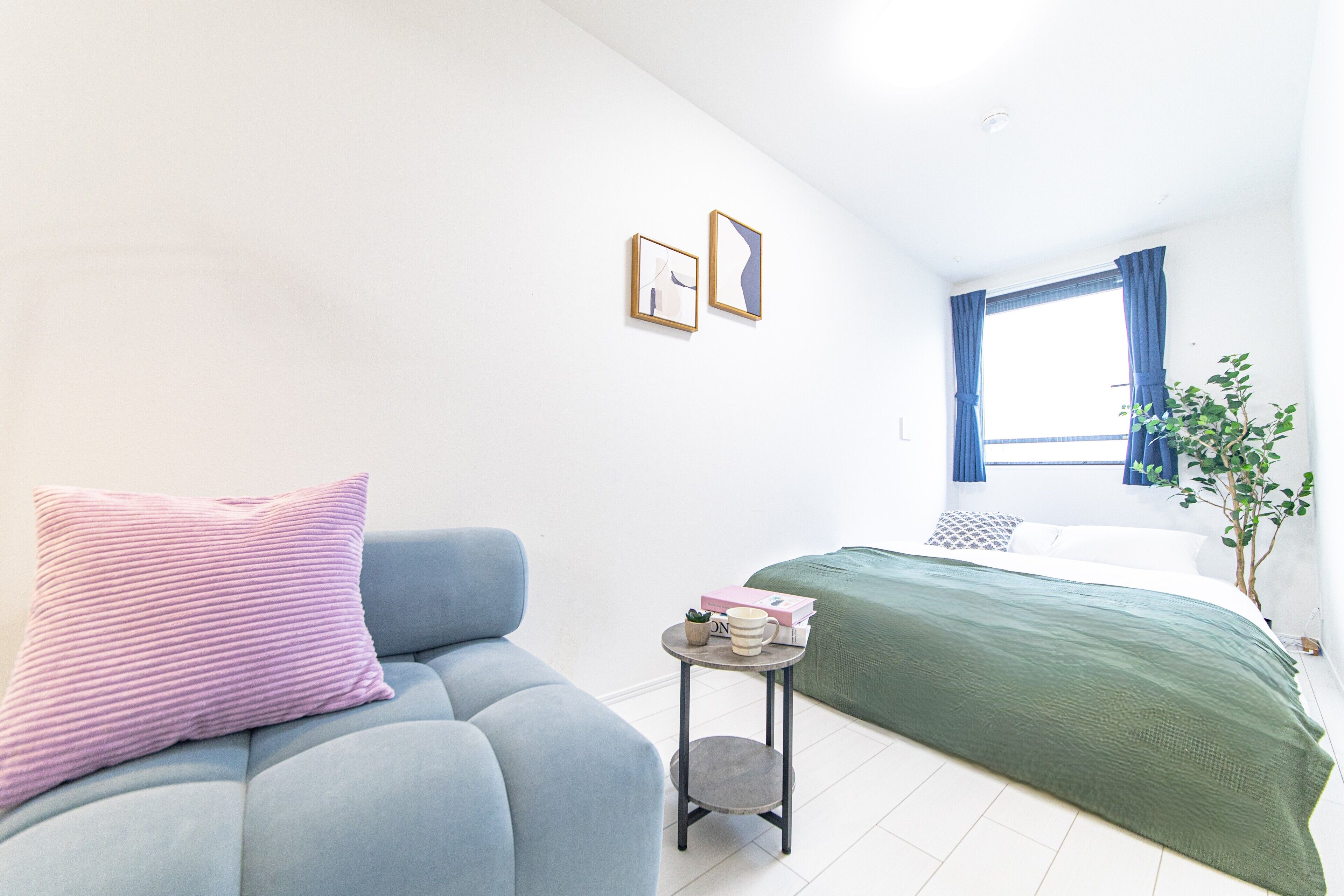 Un dormitorio moderno con sofá, cama, una mesita y una ventana con cortinas.