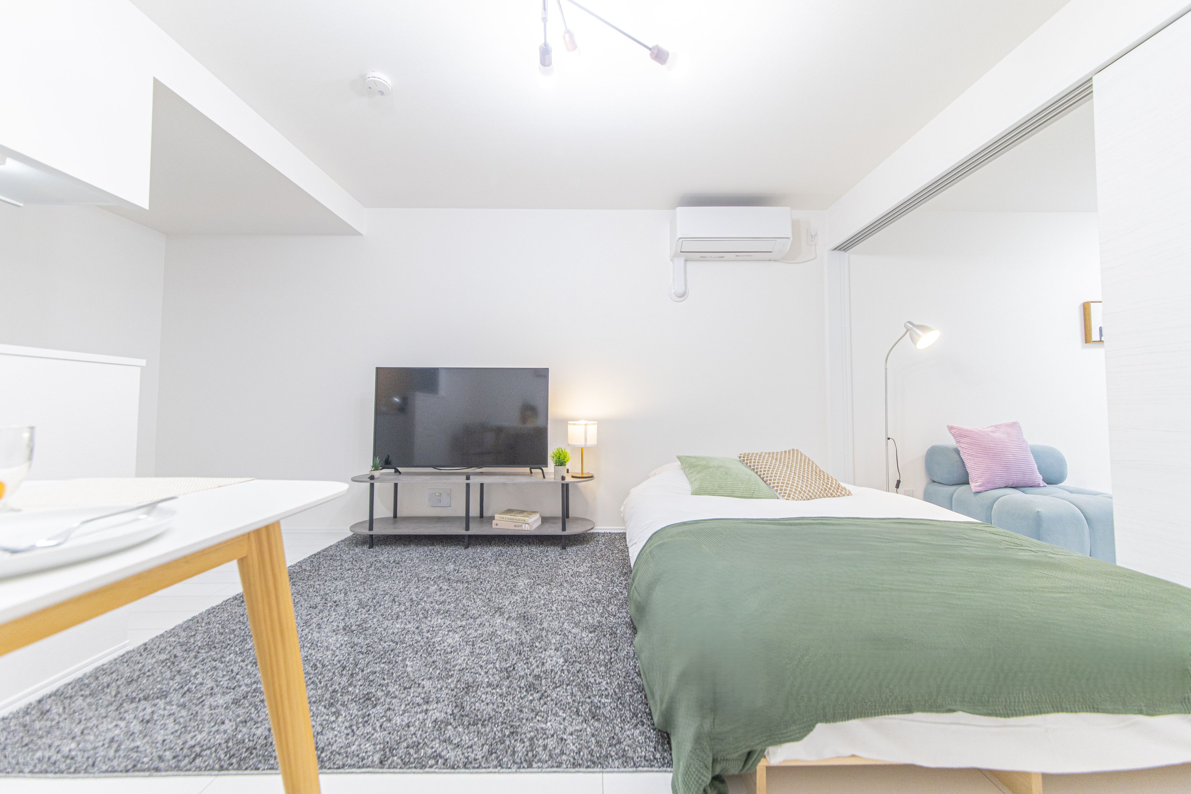 Un dormitorio moderno con una cama, un televisor, un escritorio y una lámpara.