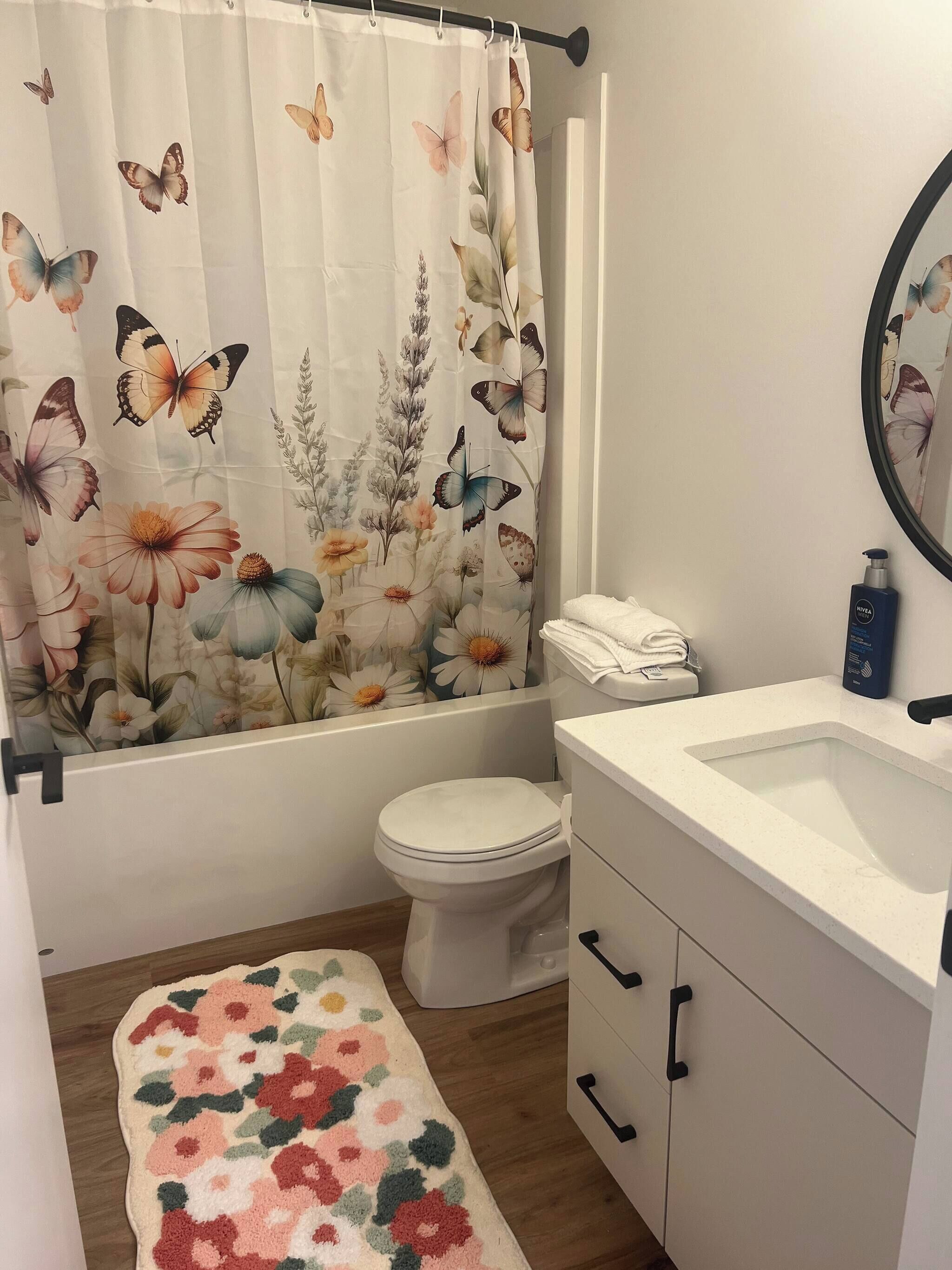 A bathroom with a floral shower curtain, a toilet, a sink, and a mirror.
