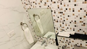 A bathroom with a white sink, a mirror, a toilet, and a shower area.