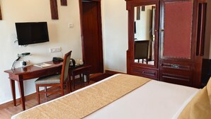 A hotel room with a bed, a desk with a chair, a television, and a wardrobe.