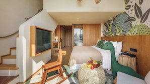 A modern hotel room with a staircase, a bed with a green dinosaur head pillow, a TV, and a wooden nightstand. - bynaked Boluo Huizhou (Huizhou)