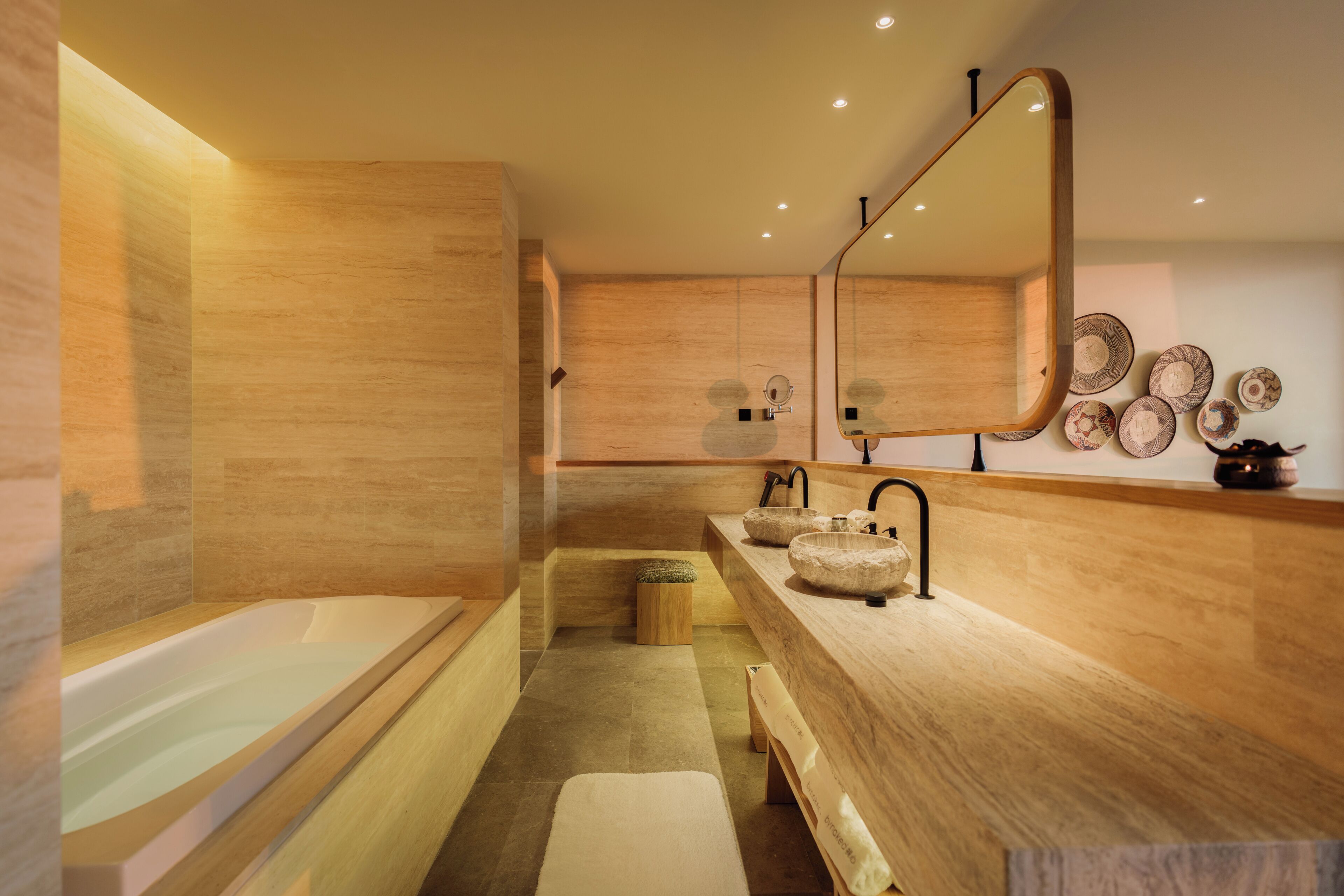 Une salle de bain moderne avec une baignoire, deux lavabos, un grand miroir et des assiettes décoratives accrochées au mur.