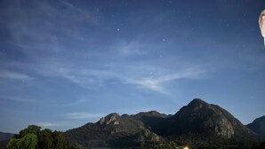 A night view of a mountainous landscape with a field in the foreground and a few buildings in the distance. - Hospedaje Valle Colibrí (Tuxpan)