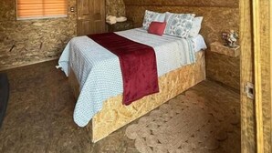 A cozy attic bedroom with a sloped ceiling, a bed with a red throw, and a small bedside table. - Hospedaje Valle Colibrí (Tuxpan)
