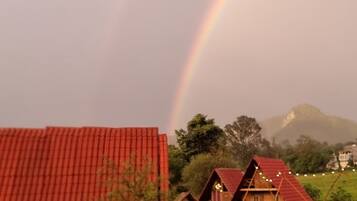 A rural landscape with a rainbow, a red-roofed barn, and traditional wooden houses.