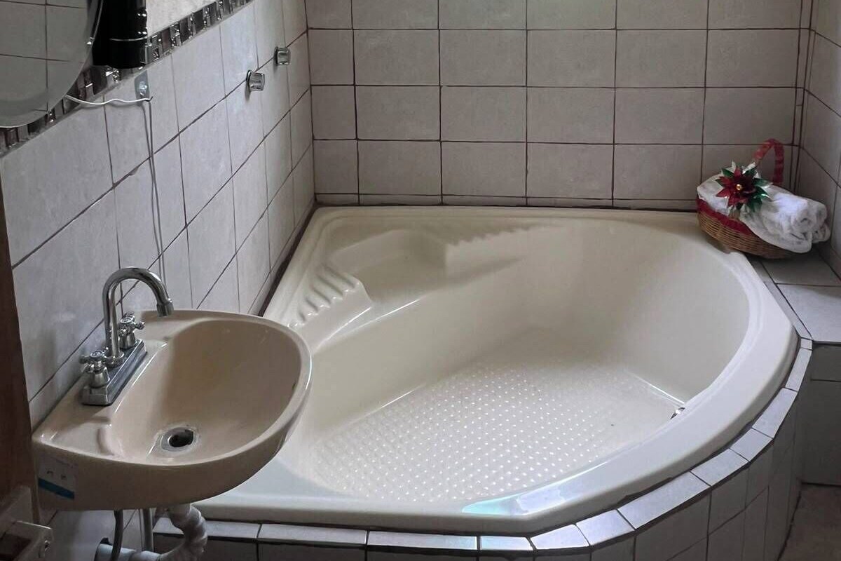 A bathroom with a bathtub, a sink, a window, and a ceiling fan.