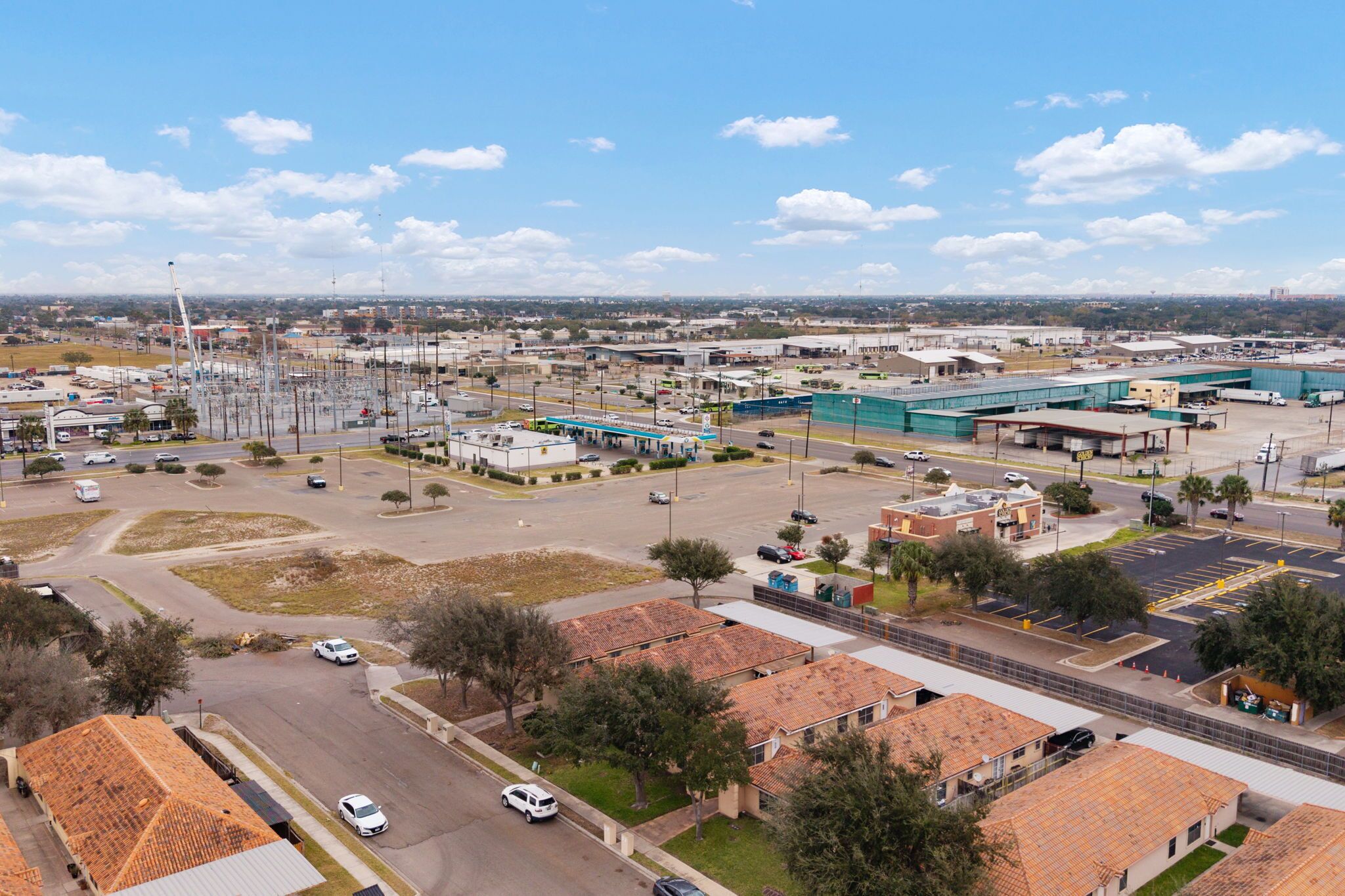 An aerial view of a commercial area with industrial buildings, parking lots, and a mix of residential and commercial structures.