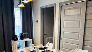 A dining area with a white table set for four, blue placemats, white chairs, and a modern pendant light fixture.