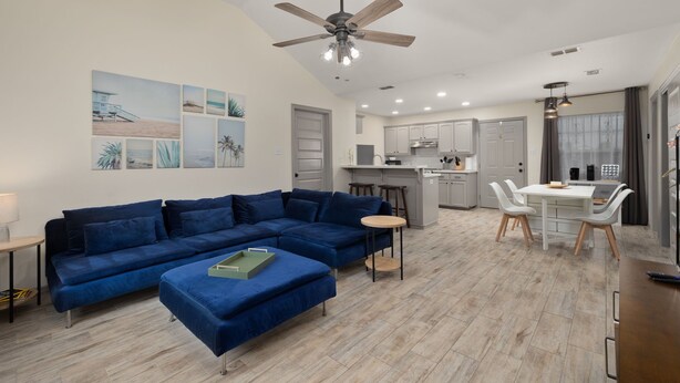 A modern living room with a blue sectional sofa, a small round table, and a ceiling fan.