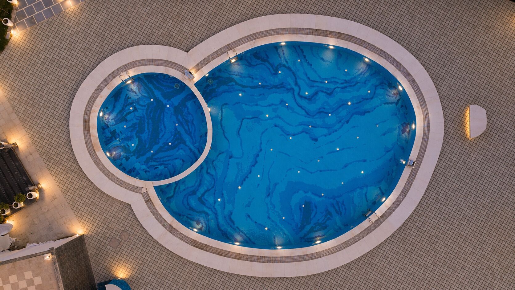 Une grande piscine intérieure de forme circulaire, avec une piscine plus petite à l’intérieur.
