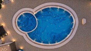 Una gran piscina interior con diseño circular e integrada una piscina más pequeña.