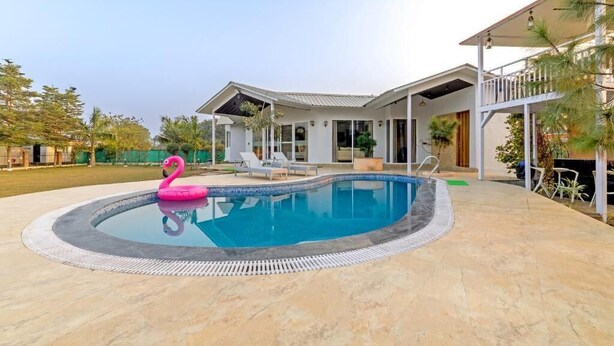 Une maison moderne dotée d’une piscine, d’un patio couvert et d’un balcon.