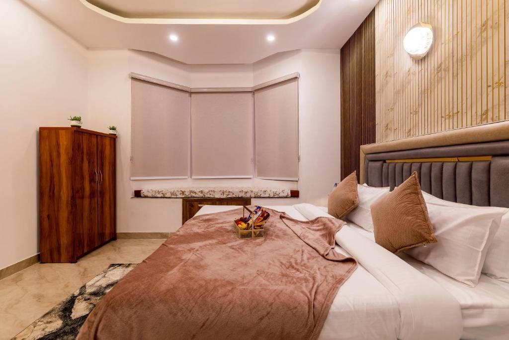 Een slaapkamer met een bed, een houten garderobe, een nachtkastje en een wandlamp.