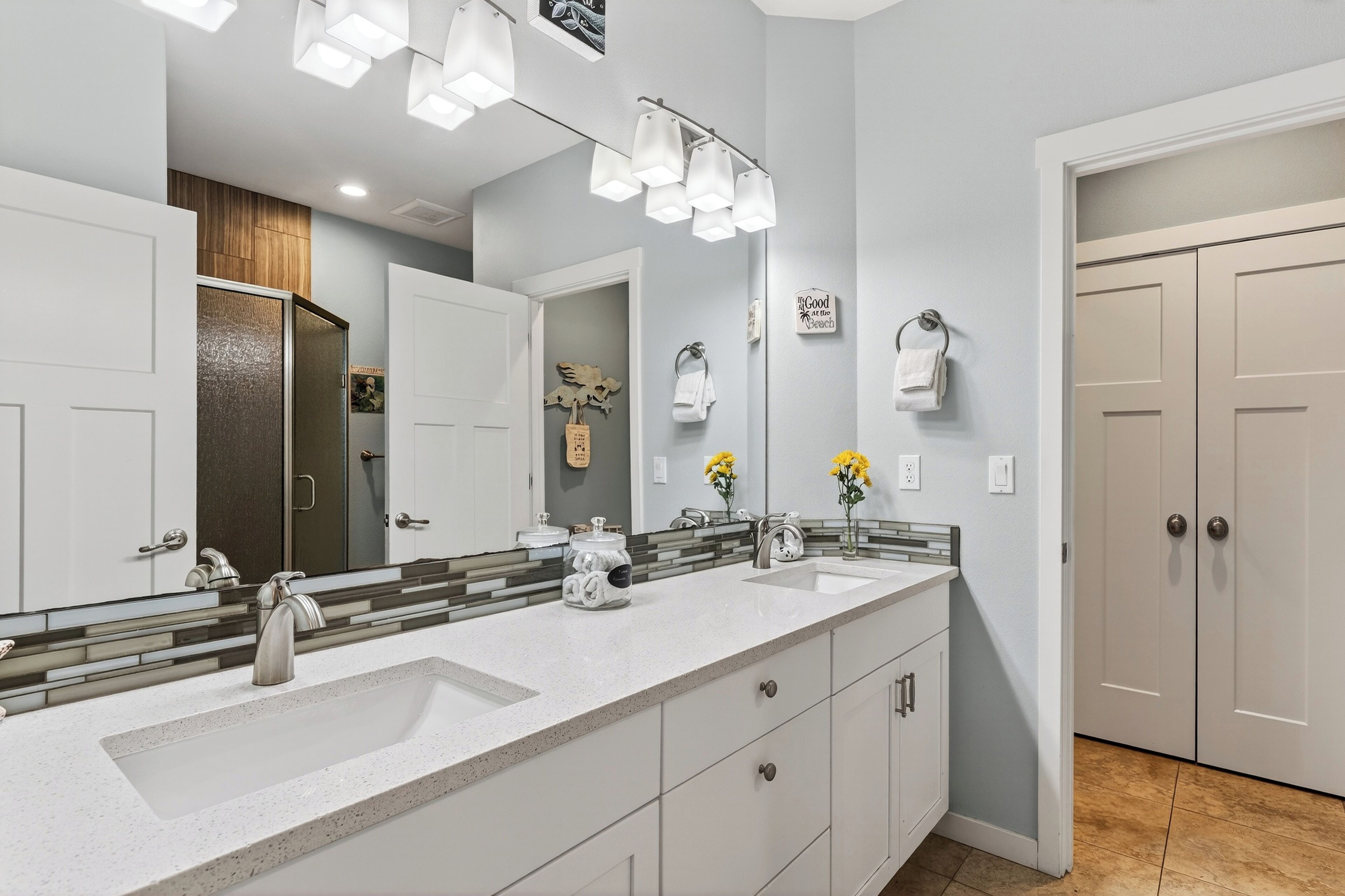 Un baño moderno con un espejo grande, dos lavamanos y un mueble de tocador con cajones.