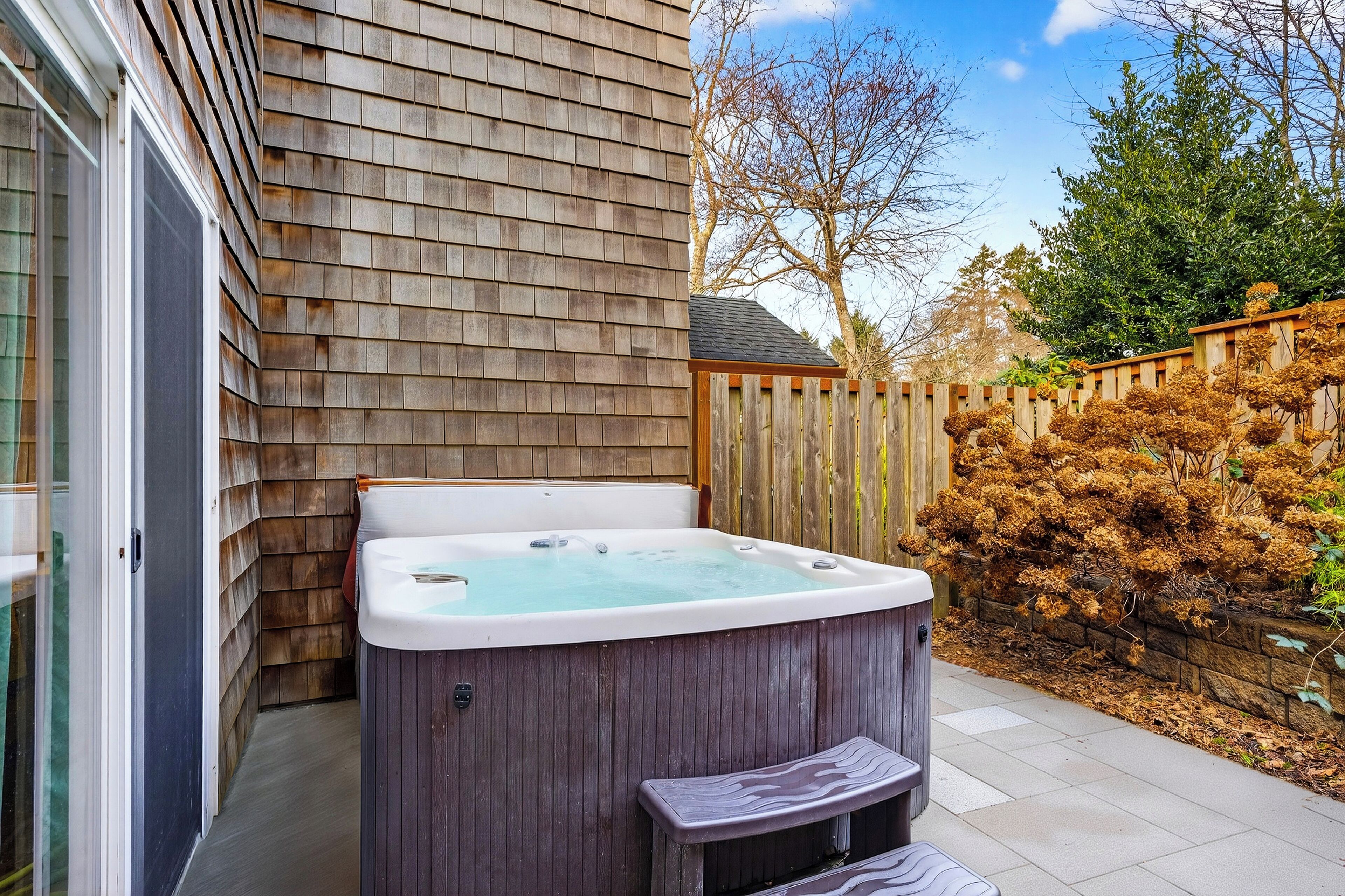 Ein Whirlpool in einem Garten mit Holzwandverkleidung und Holzzaun.