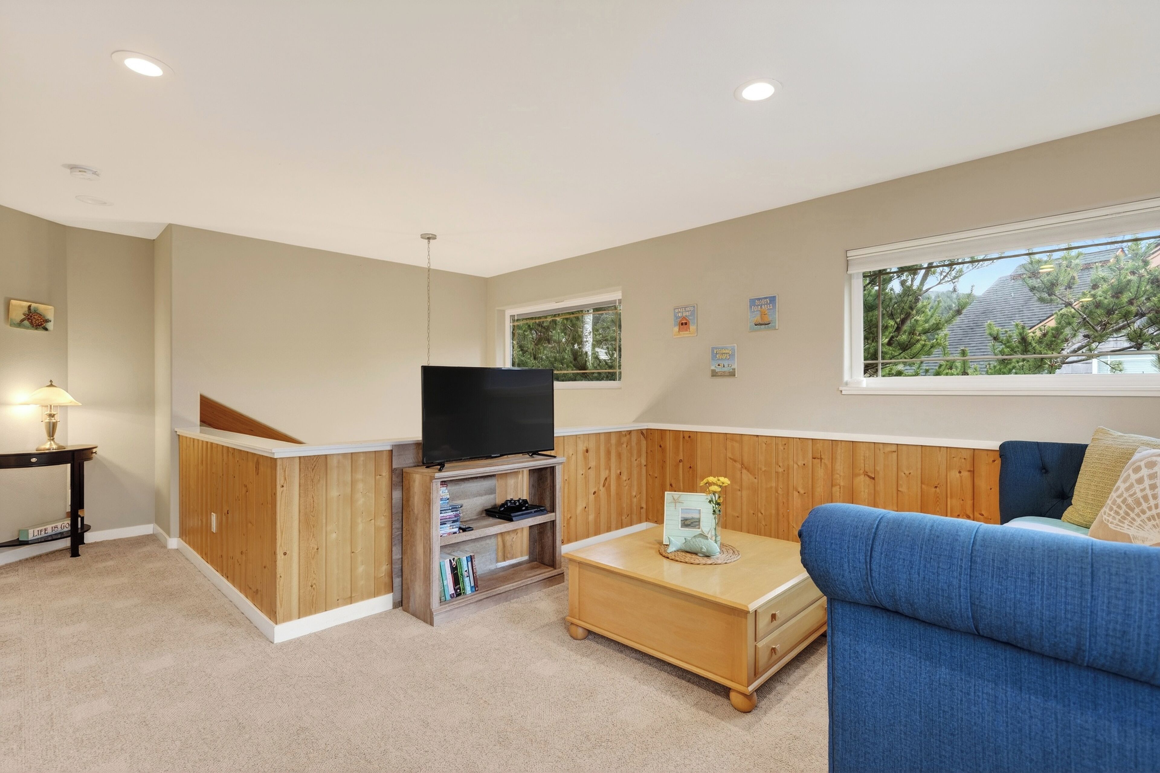 A living room with a TV on a wooden stand, a blue sofa, and a small coffee table.
