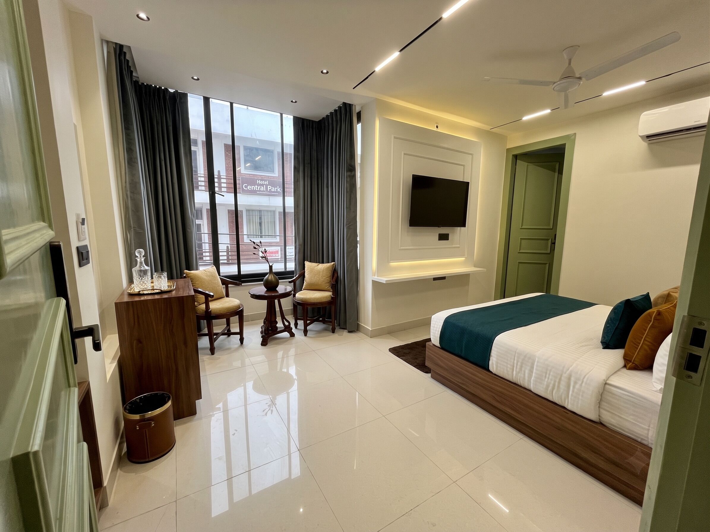 Quarto de hotel moderno com cama, televisão na parede, secretária com cadeira e vista para o exterior.