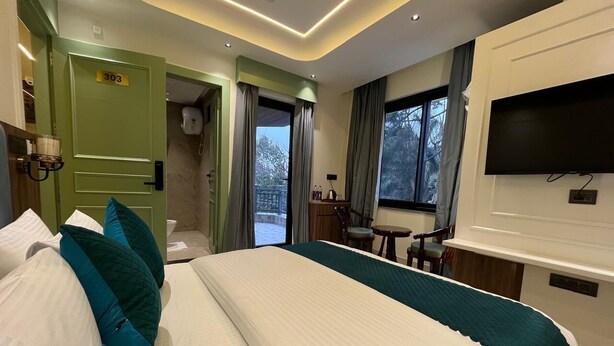 Ein Hotelzimmer mit einem großen Bett, einem Schreibtisch, einem Fernseher und Blick ins Freie.