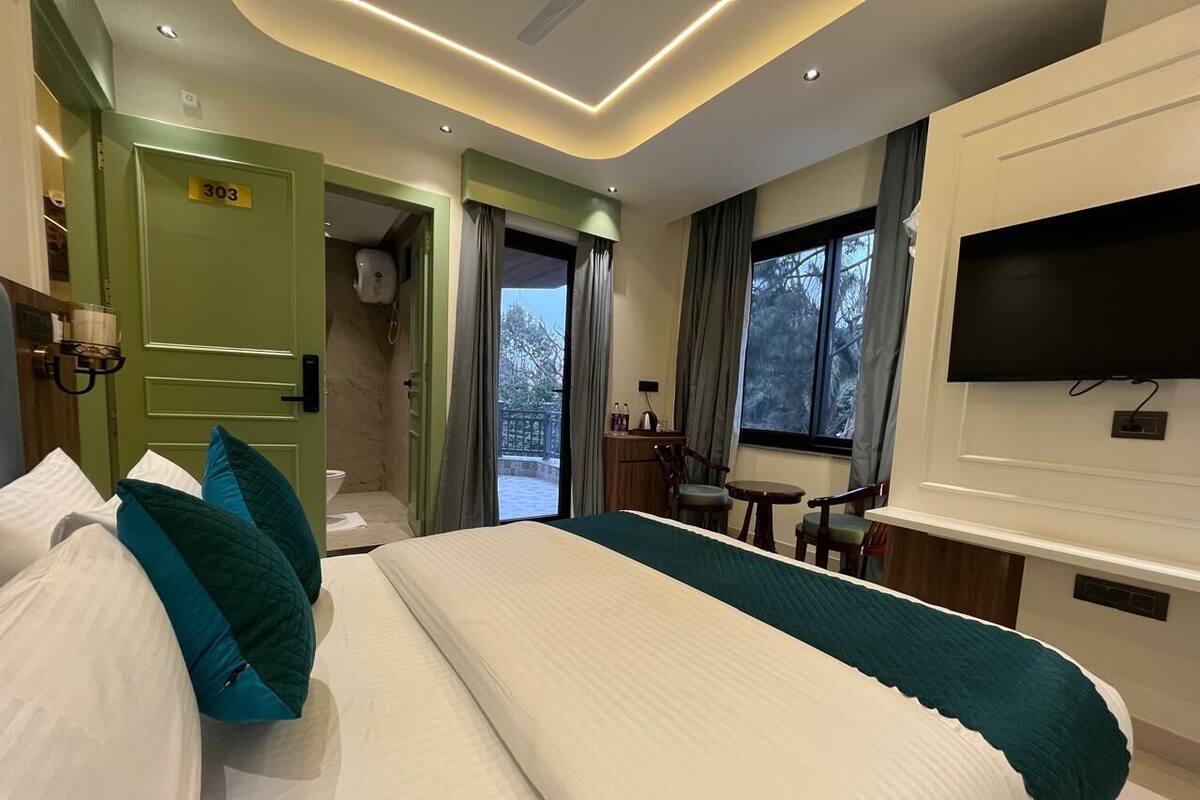 Habitación de hotel con una cama grande, un escritorio, un televisor y vistas al exterior.