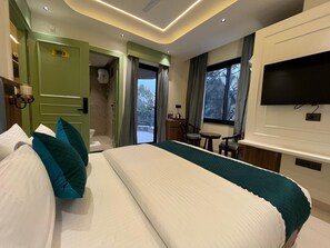 Habitación de hotel con una cama grande, un escritorio, un televisor y vistas al exterior.