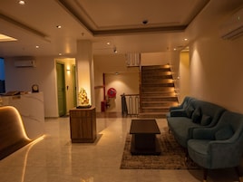 Una sala de estar moderna con una recepción, una escalera y un sofá azul.