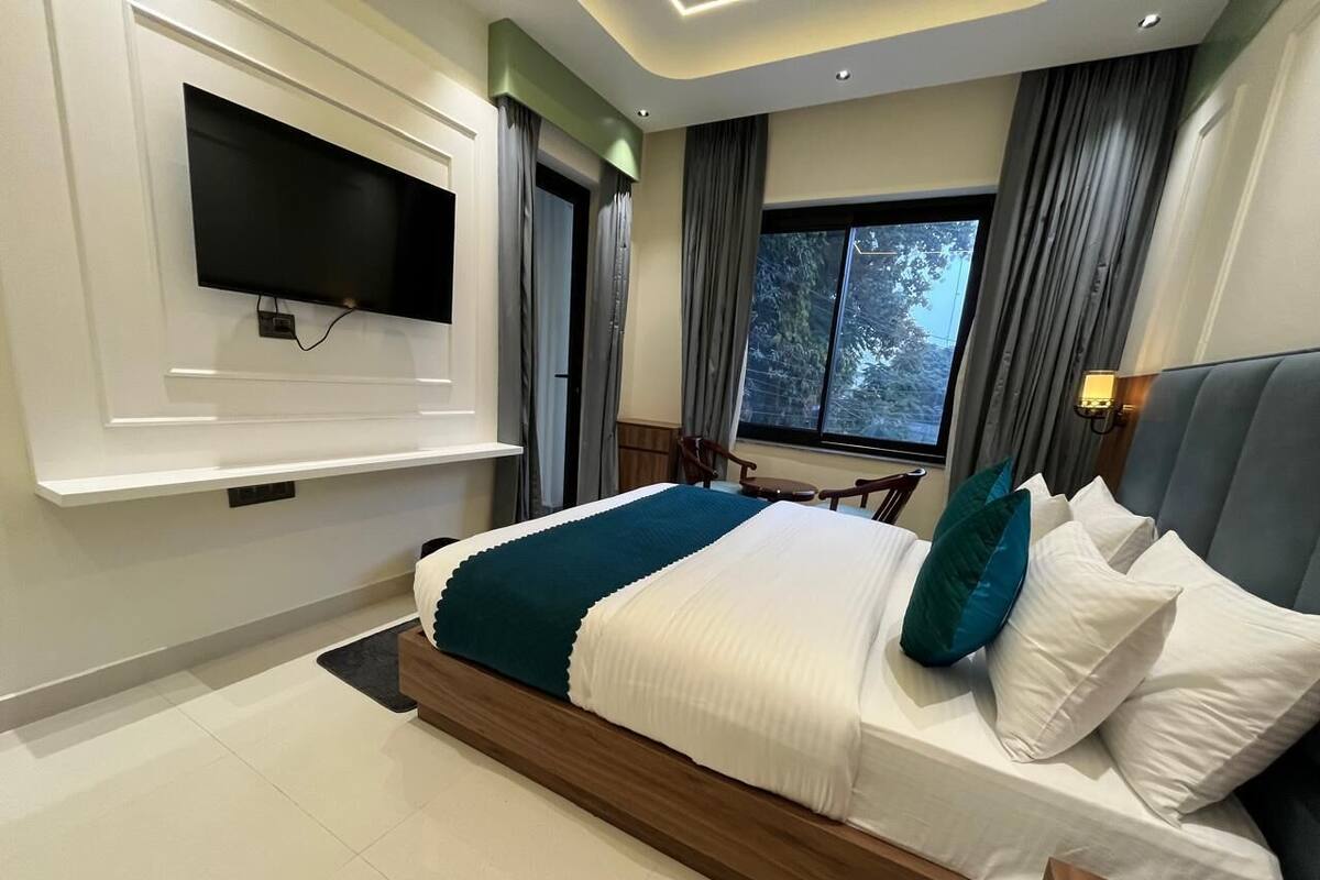 A modern bedroom with a large bed, a mounted TV, and a window with curtains.