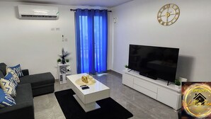 Una sala de estar moderna con un sofá, una mesa de centro, un televisor y un aire acondicionado instalado en la pared.