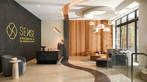 Un moderno vestíbulo de hotel con mostrador de recepción, zona de estar y grandes ventanales.