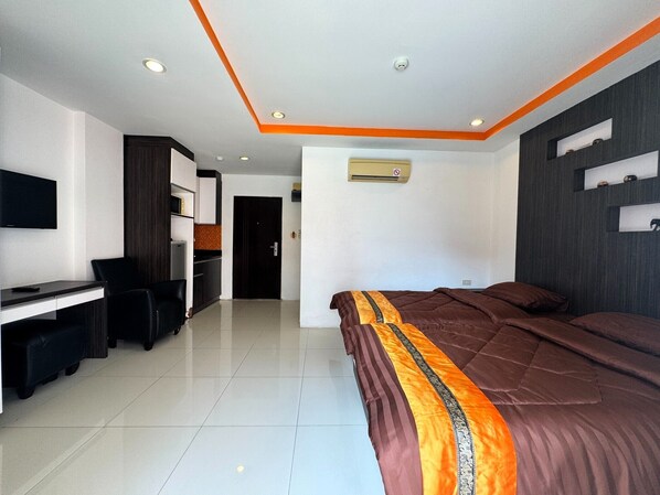 Een moderne hotelkamer met een bed, bureau, stoel, een televisie en een kledingkast.