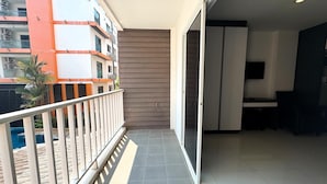Un balcone con vista su un edificio, una porta scorrevole in vetro e un pavimento piastrellato.