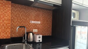 A kitchen with a tiled backsplash, a stainless steel sink, a kettle, a toaster, and a microwave. - Pool-View Studio with Balcony - New Nordic VIP 4, Pratumnak (Muang Pattaya)