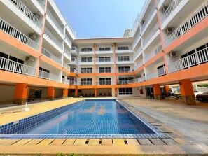 Un immeuble à plusieurs étages doté d’une cour intérieure où se trouve une piscine.