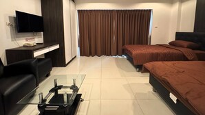 A modern hotel room with a bed, a desk with a flat-screen TV, a sofa, and a glass coffee table. - Pool-View Studio with Balcony - New Nordic VIP 4, Pratumnak (Muang Pattaya)