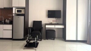 A modern kitchen with a microwave, refrigerator, and a dining area with a chair and table. - Pool-View Studio with Balcony - New Nordic VIP 4, Pratumnak (Muang Pattaya)