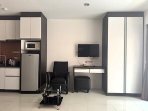 A modern kitchen with a microwave, refrigerator, and a dining area with a chair and table. - Pool-View Studio with Balcony - New Nordic VIP 4, Pratumnak (Muang Pattaya)