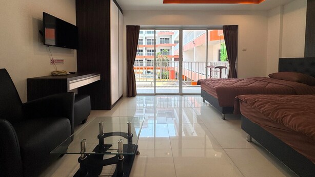 A modern hotel room with a glass coffee table, a sofa, a bed, and a TV mounted on the wall. - Comfortable Pool-View Studio with Balcony - Pratumnak, Pattaya (Muang Pattaya)