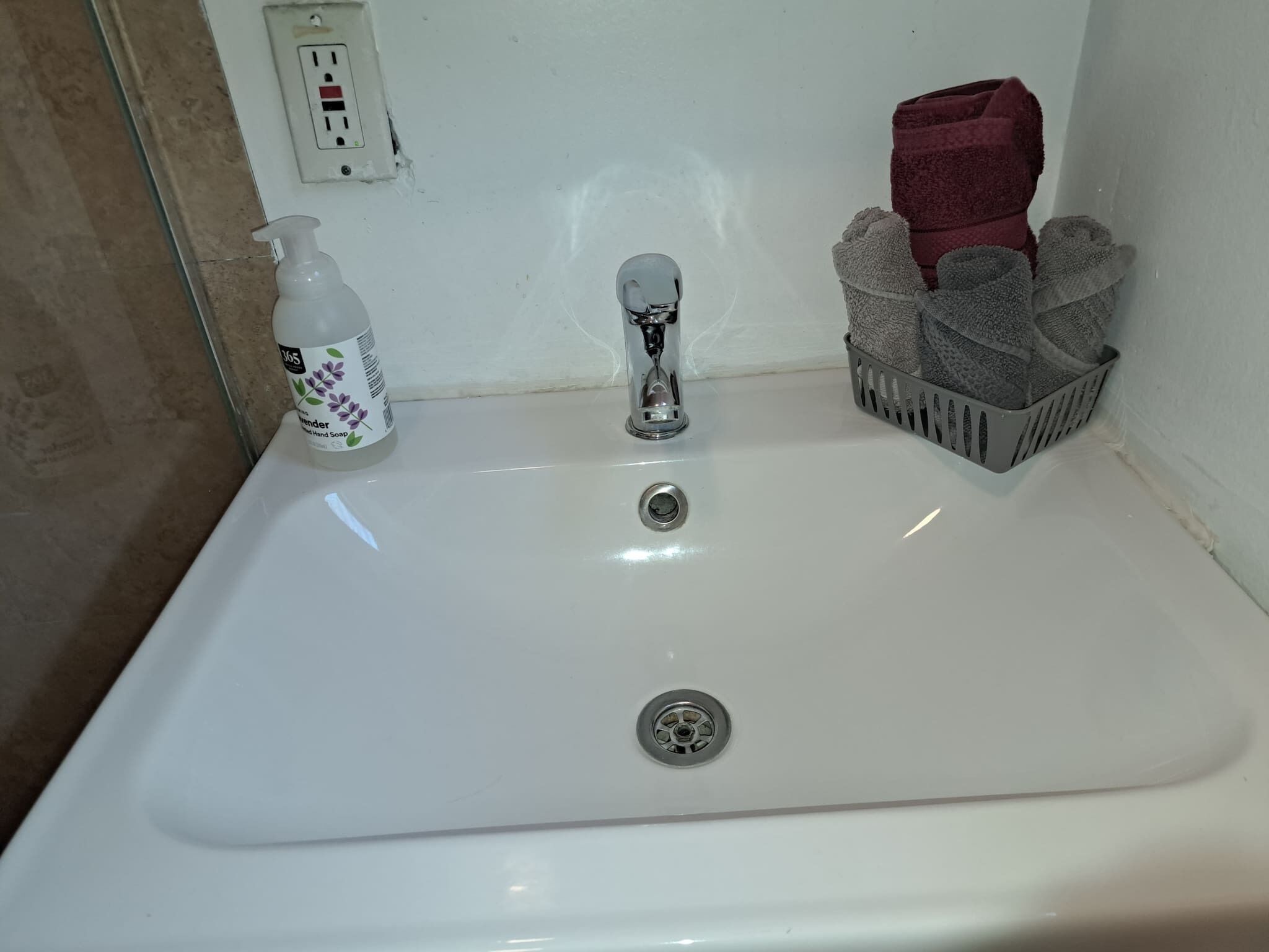 A bathroom sink with a faucet, a soap dispenser, and a towel rack with towels.