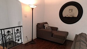 A living room with a brown sofa, a floor lamp, a round mirror, and a staircase with a black railing. - 3 bedroom plus 2 baths in Beverly hills (Beverly Hills)