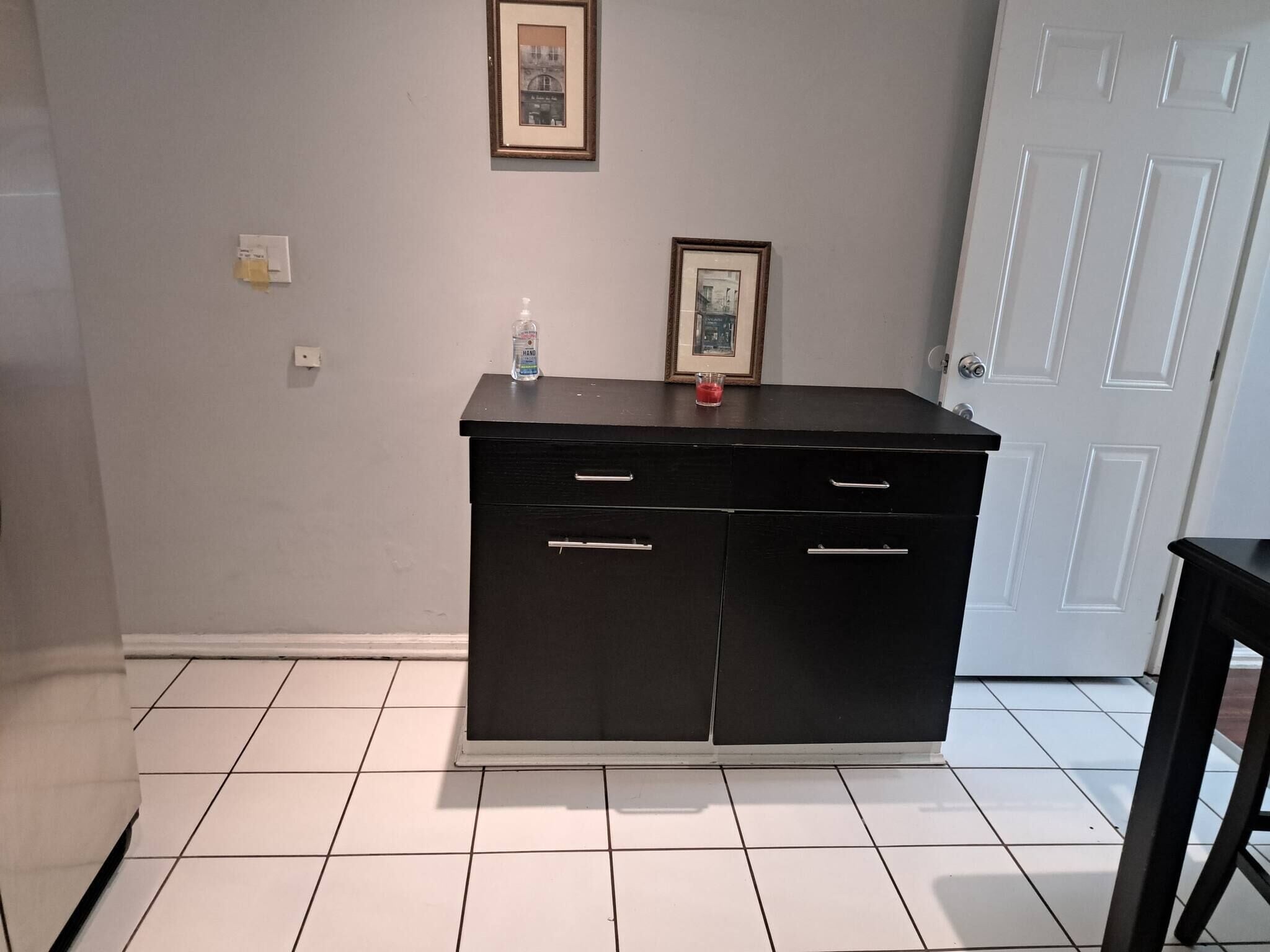 A room with a black cabinet, a framed picture on the wall, and a white door.