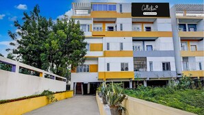 A multi-story hotel with a modern design, featuring a mix of white and yellow colors, and a central entrance with a staircase. - Collection O Sunrise Point Serenity Beach (Vanur)