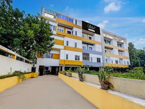 A multi-story hotel with a modern design, featuring a prominent signboard and a well-maintained outdoor area with potted plants.
