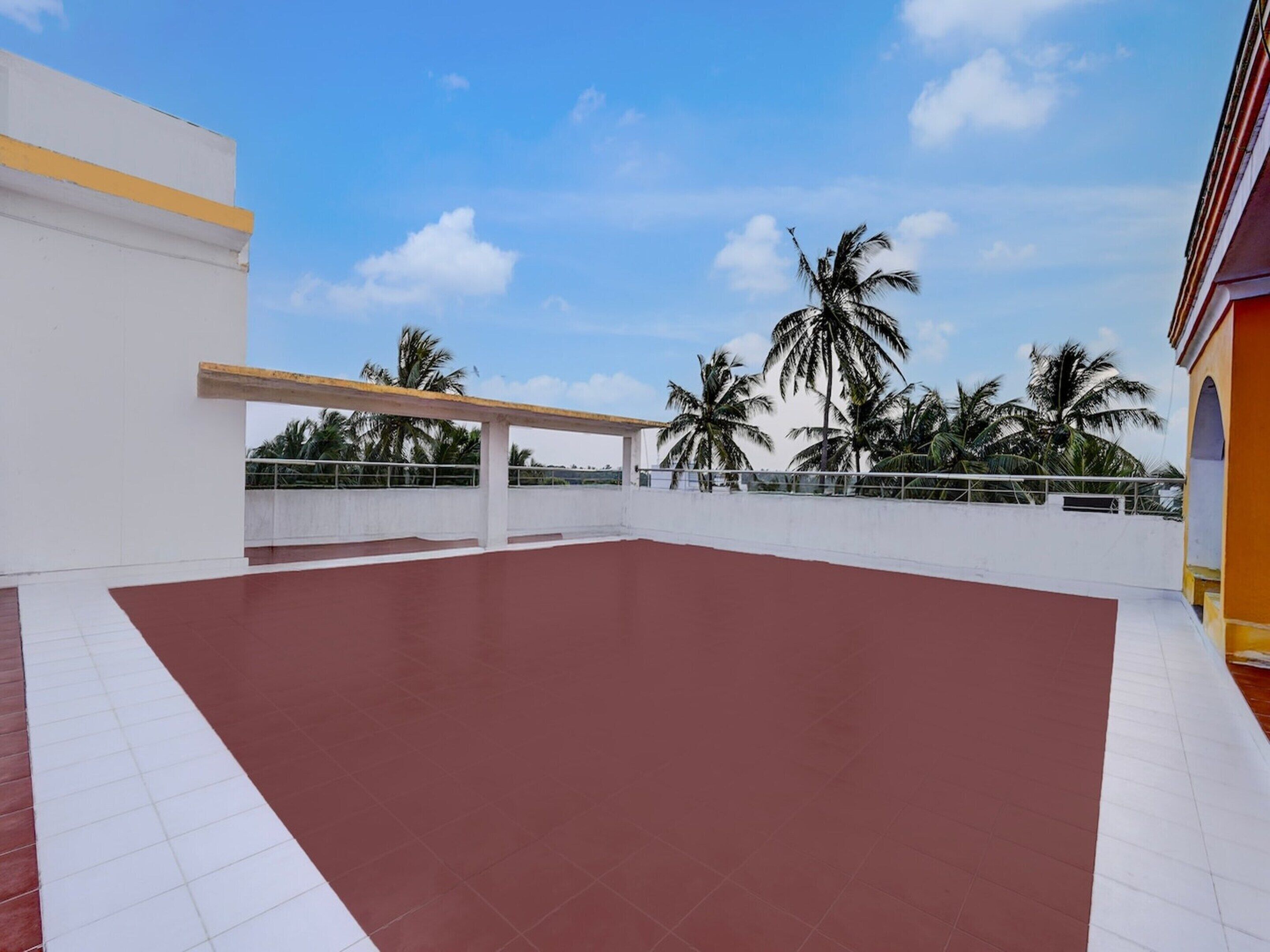 A rooftop terrace with a red floor, white walls, and a yellow stripe.