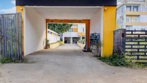 A building entrance with a covered walkway, a gated driveway, and a view of a multi-story building in the background. - Collection O Sunrise Point Serenity Beach (Vanur)