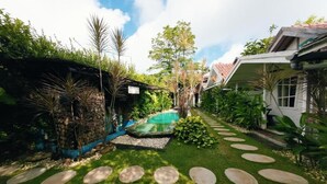 A well-maintained garden with a swimming pool, stone pathways, and lush greenery. - Habana Hotel  (Kuta)